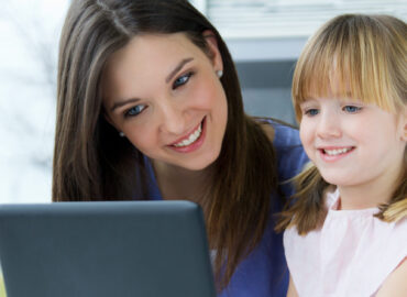 Portrait of Mother and daughter using laptop in the kitchen